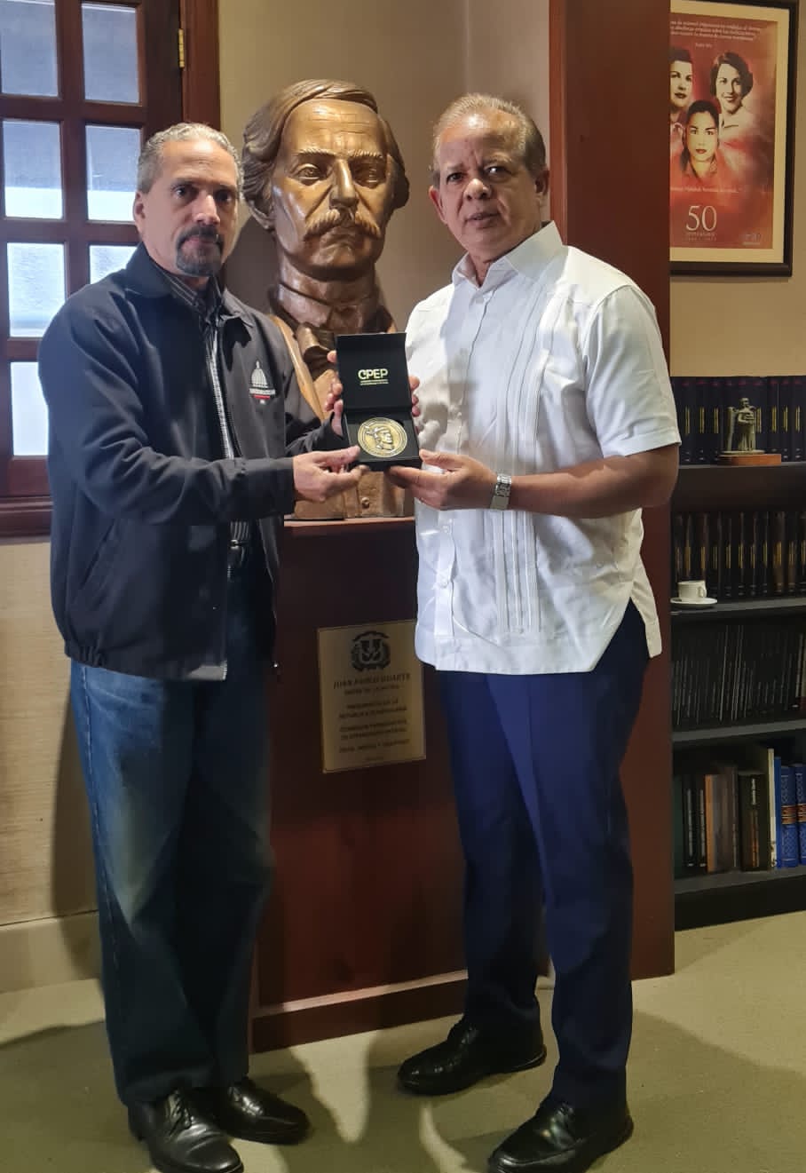 Juan Pablo Uribe, presidente de Efemérides Patrias, en una reunión de trabajo le entrega la medalla Enriquillo, de la dominicanas a Aníbal Belliard, Director Operativo de la Presidencia.